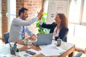 Business team high-fiving in office celebrating achievement and teamwork.