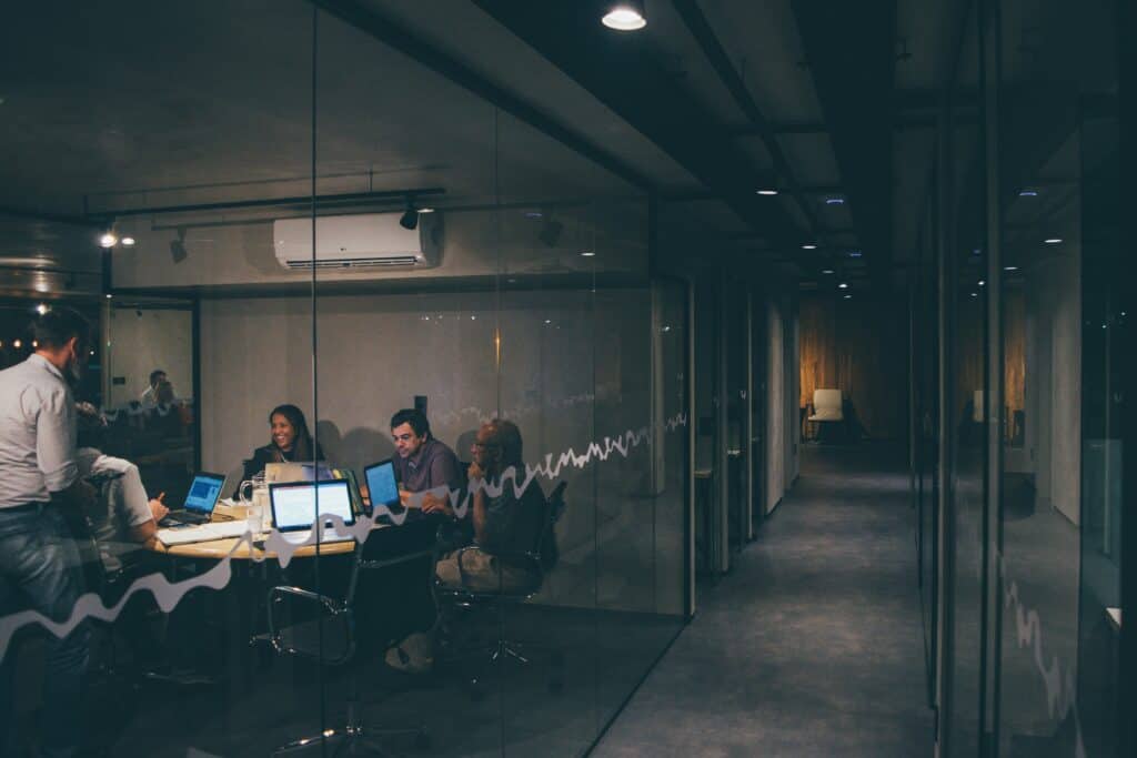 Modern office space with team collaborating on laptops and digital devices.