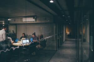 Modern office space with team collaborating on laptops and digital devices.