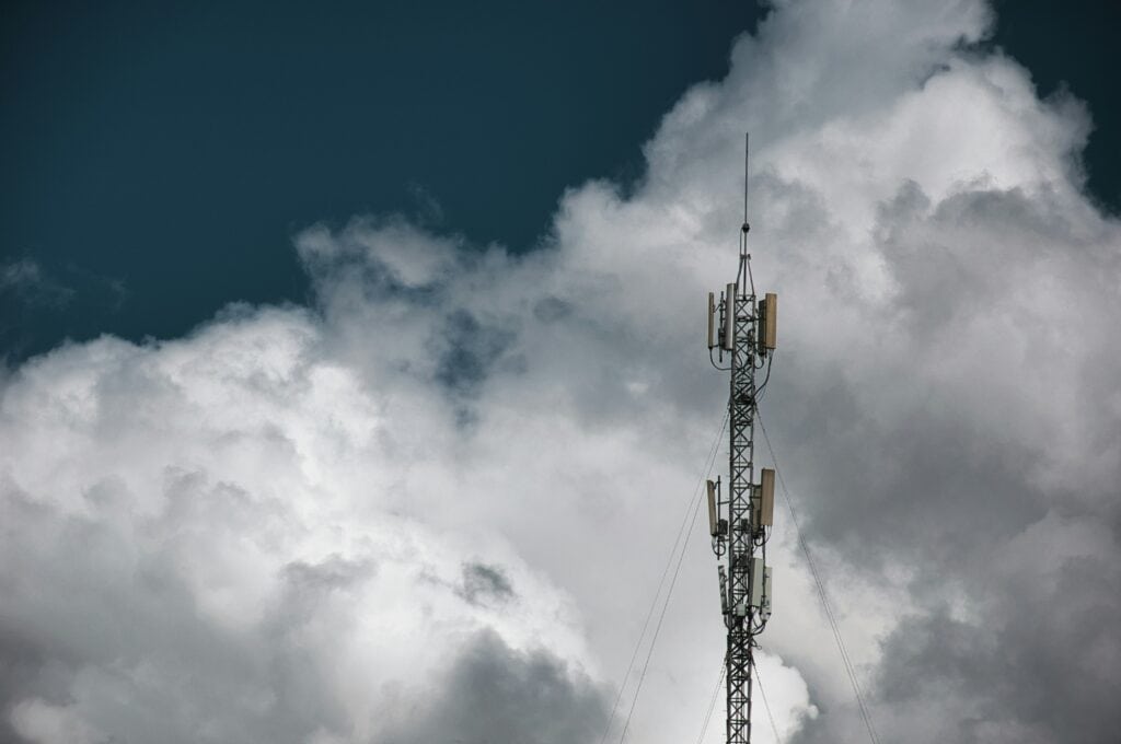 Communication tower with antennas under cloudy sky.