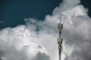 Communication tower with antennas under cloudy sky.